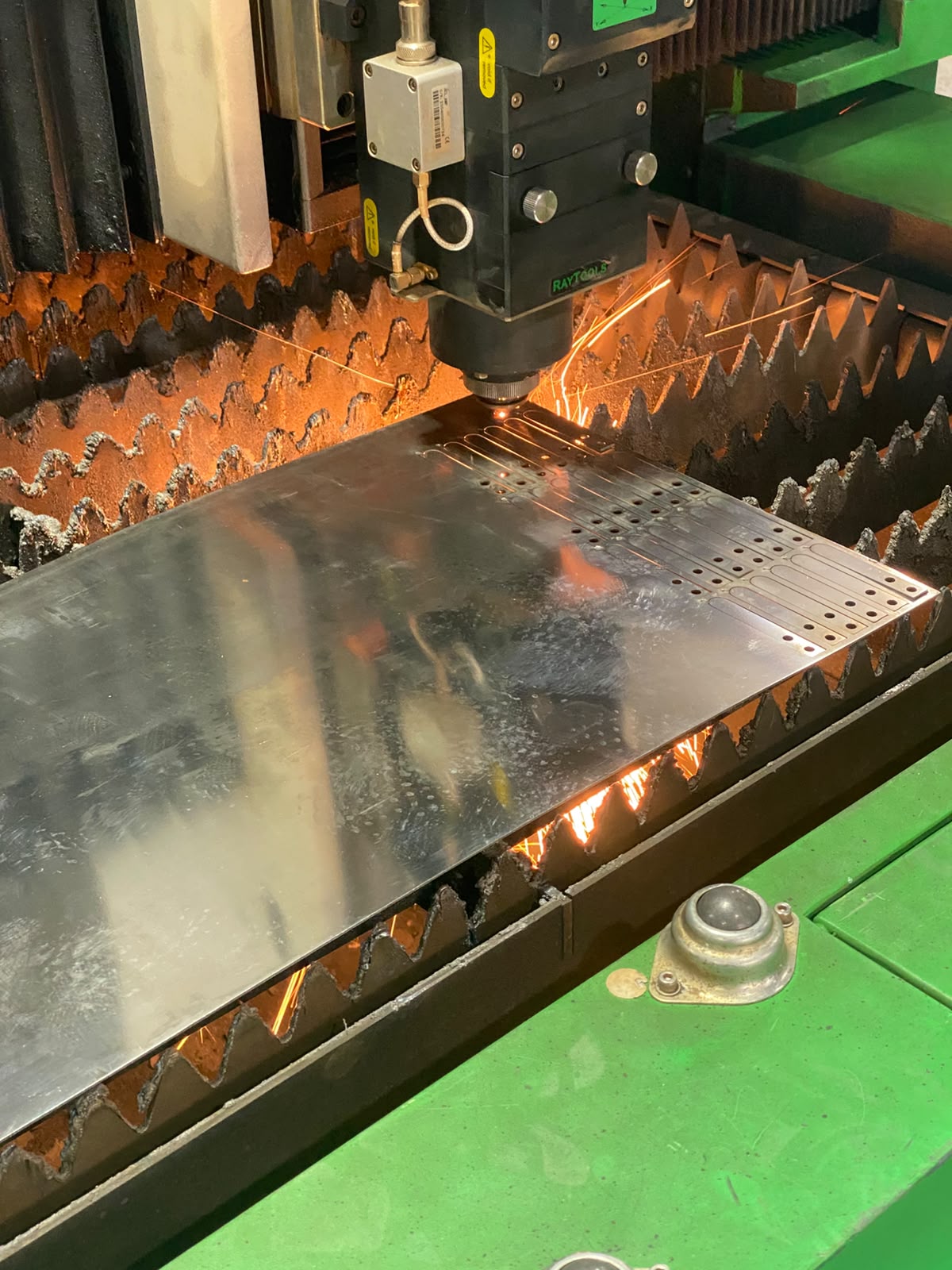 Máquina executando corte a laser de precisão em chapa de aço inox